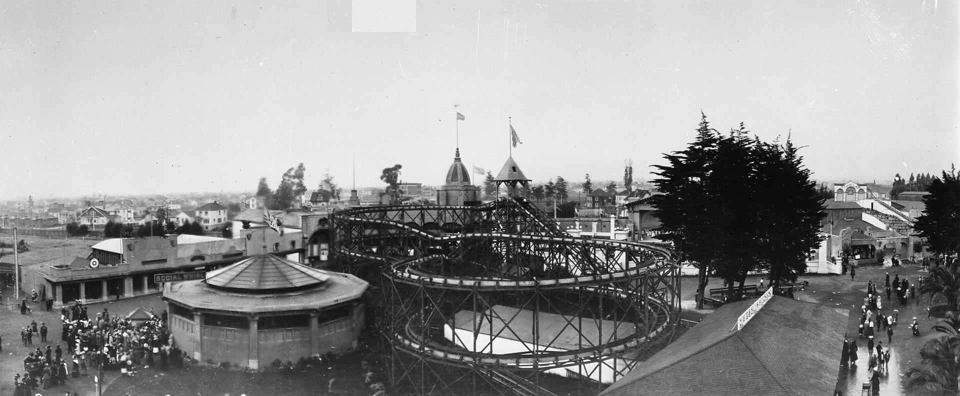 Idora Park, aerial view. Features a density of amusement park rides and rollercoasters, with the East Bay hills in the background.