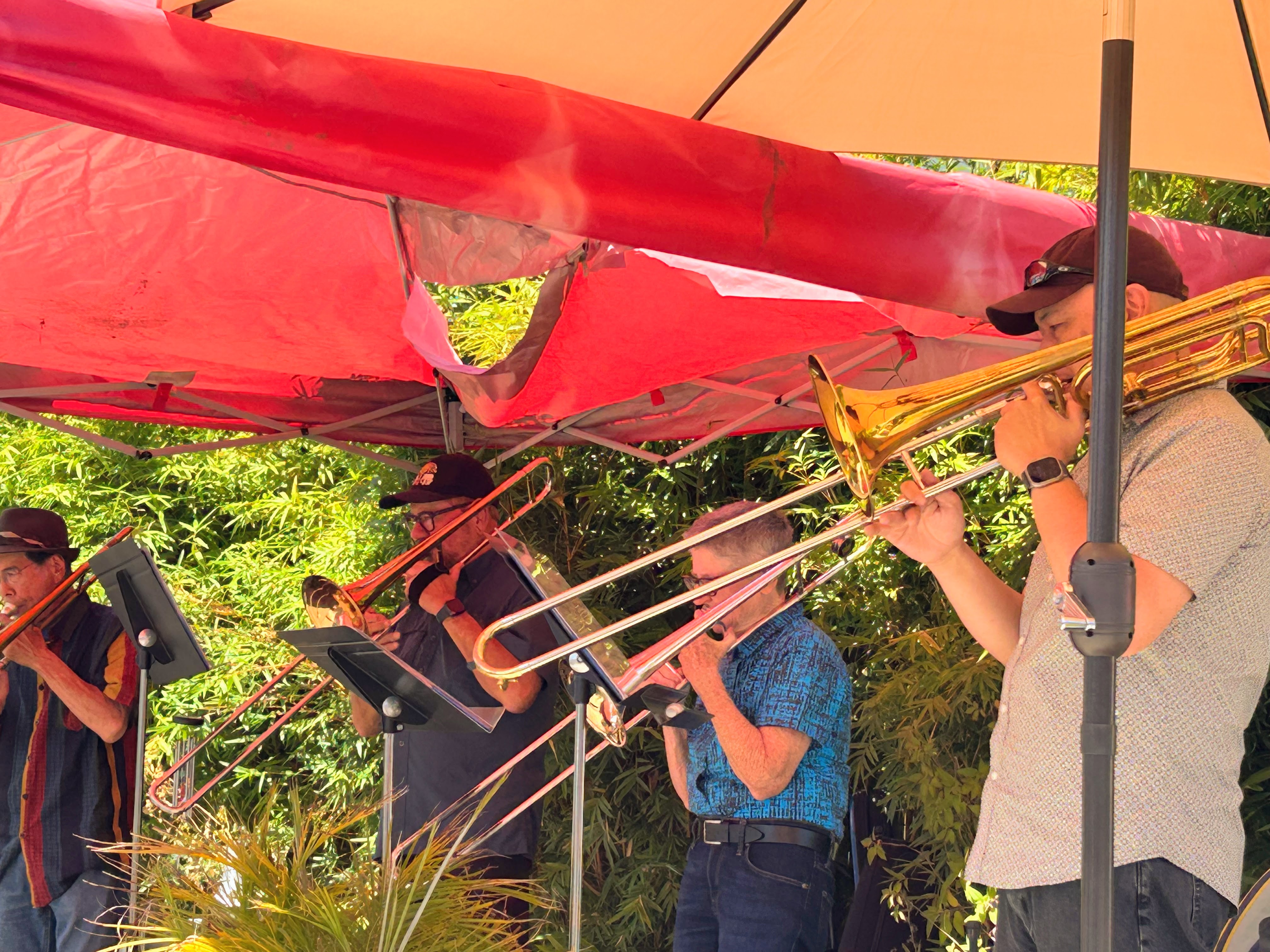 A four piece trombone band named Trombonga plays underneath a red tent.